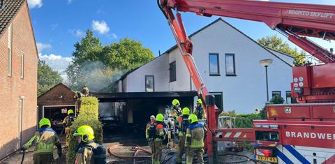 brandweerlieden blussen met hoogwerker de garage van de woning