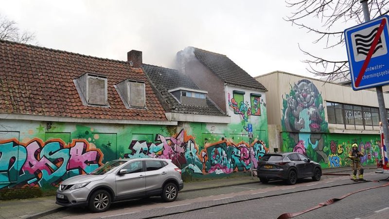 Leegstaand pand met graffiti en rookwolken uit het pand. 