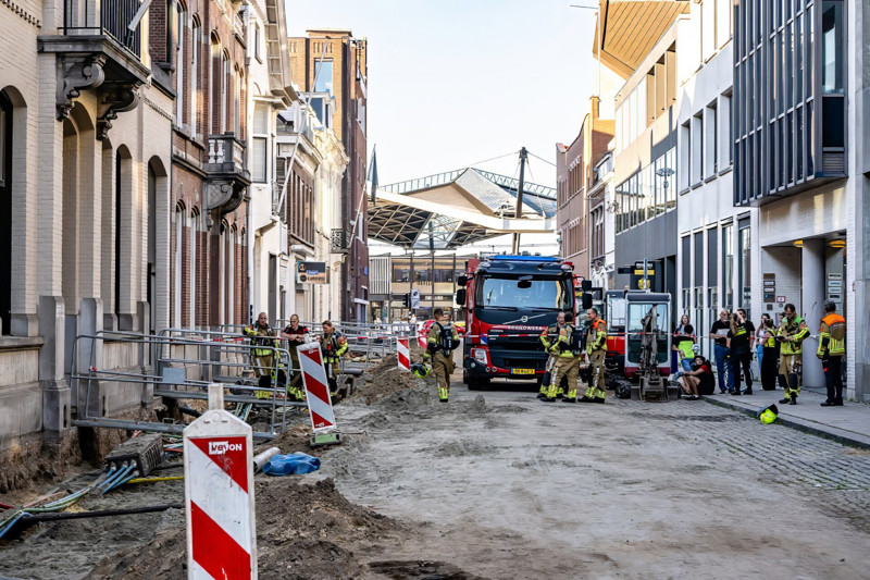 Brandweerauto in straat met werkzaamheden waar brandweermensen naar gaslek zoeken