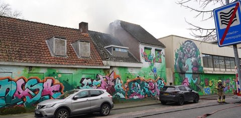 Leegstaand pand met graffiti en rookwolken uit het pand. 