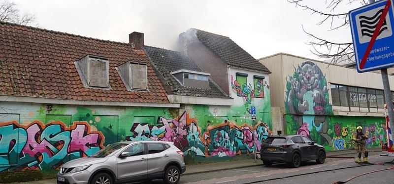 Leegstaand pand met graffiti en rookwolken uit het pand. 