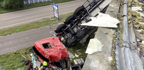 Vrachtwagen ligt op zijkant naast de weg naar beneden