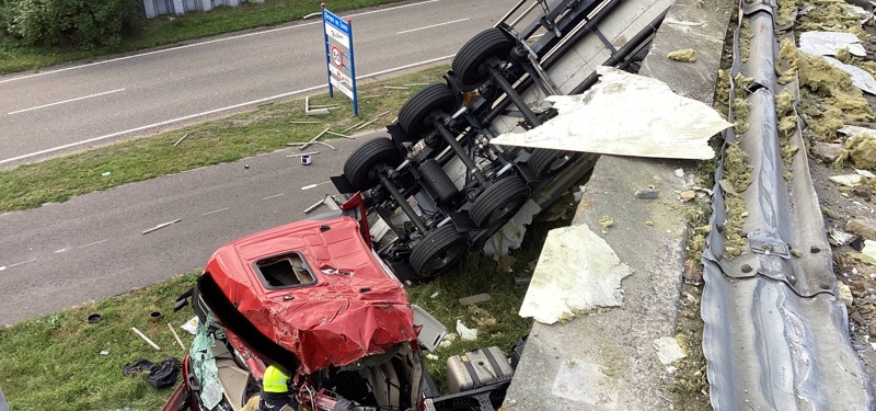 Vrachtwagen ligt op zijkant naast de weg naar beneden